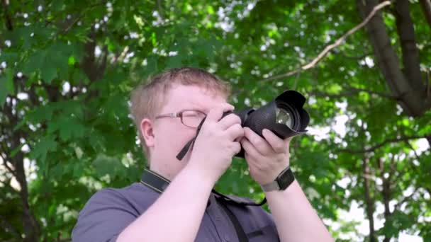 Młody człowiek robi zdjęcia w parku — Wideo stockowe