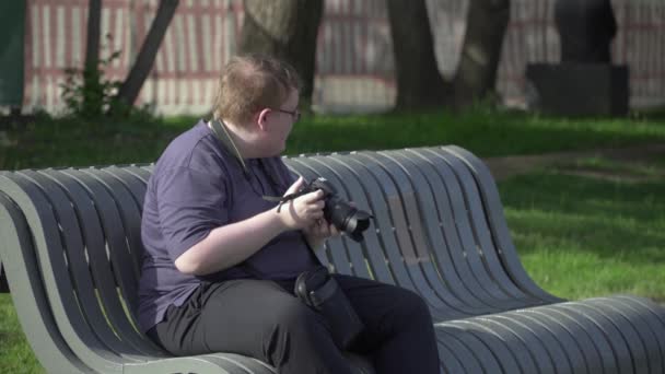 Молодой человек фотографирует в парке — стоковое видео