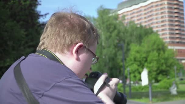 Молодий чоловік фотографує в парку — стокове відео