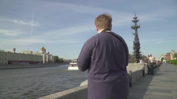 Молодой человек фотографирует в парке — стоковое видео