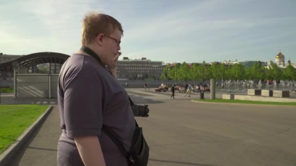 Молодий чоловік фотографує в парку — стокове відео