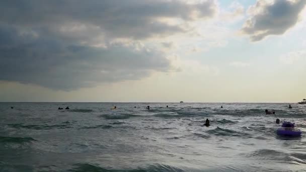 Folk svømmer om kvelden i havet. Langsom bevegelse – stockvideo