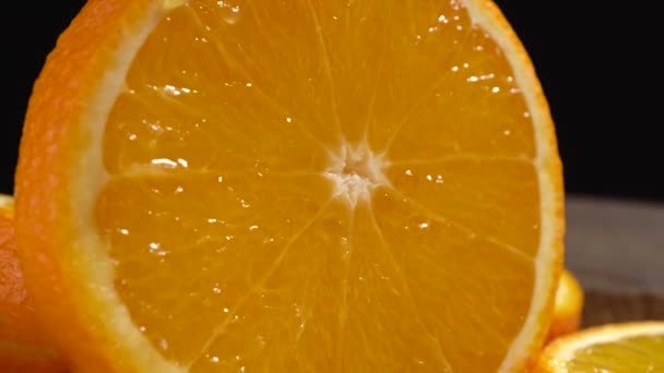 黒の背景にスライスされたオレンジのクローズアップ — ストック動画
