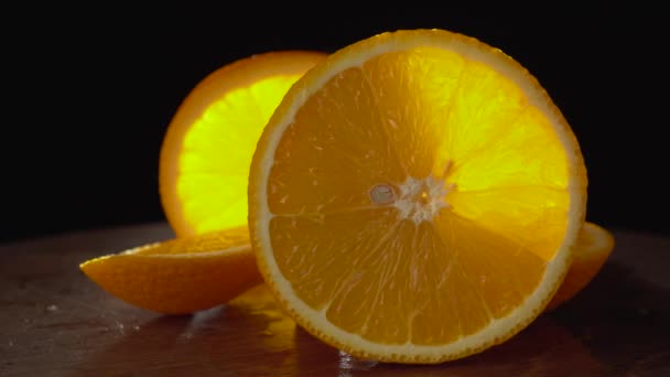 Primer plano naranja en rodajas sobre un fondo negro — Vídeo de stock