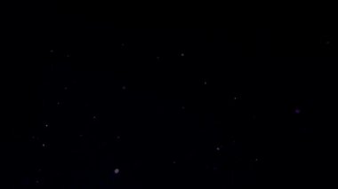 Parçacıklar siyah arka planda Bokeh arasında rastgele hareket ederler. Soyut dekoratif arkaplan