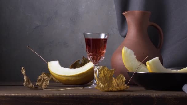 Natura morta con melone affettato, brocca di argilla di vino e foglie autunnali — Video Stock