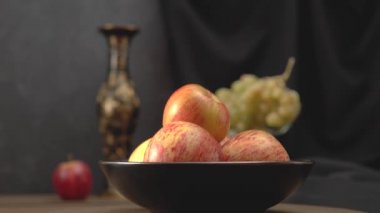 Karanlık bir arka planda elmalar ve üzümlerle dolu bir hayat