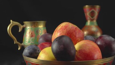 Karanlık bir arka planda erik ve elmalarla dolu bir hayat