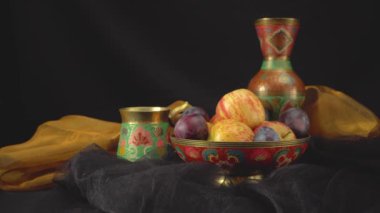 Karanlık bir arka planda erik ve elmalarla dolu bir hayat