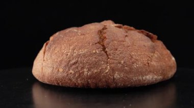 Yuvarlak çavdar ekmeği siyah zemine yakın.