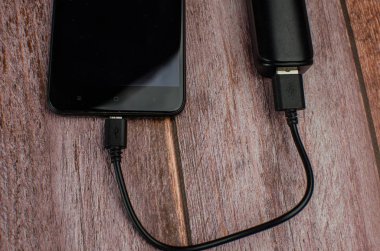 Powerbank ve ahşap masa üzerinde cep telefonu. Metin için yer kopyalayın