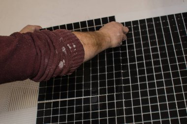 Ev onarım: duvara mozaik çini yükleme. Bir işçi duvar çentikli bir mala kullanarak yapıştırıcı ile kapsar..