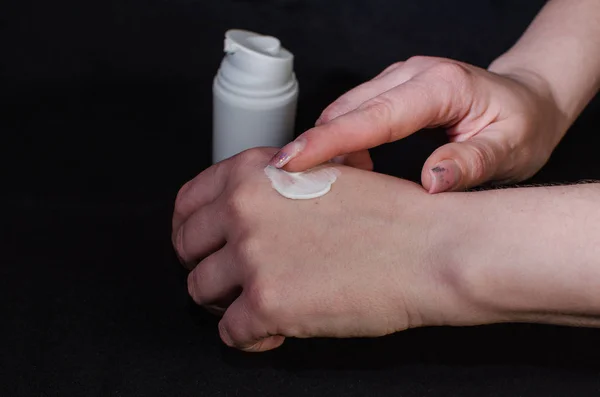 Smear cream on woman hand. Lotion for face or body.