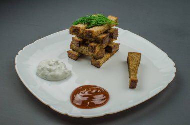 Tost kızartma tavası baharatlar ile üzerinde yanmış. Sarımsak sosu ve barbekü sosu ile beyaz bir tabakta servis