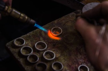 Profesyonel aletlerle mücevher yapımı. Makro atış. El yapımı kuyumcu, mücevher üretimi. Eriyen metal