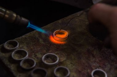 Profesyonel aletlerle mücevher yapımı. Makro atış. El yapımı kuyumcu, mücevher üretimi. Eriyen metal