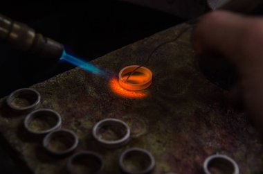 Profesyonel aletlerle mücevher yapımı. Makro atış. El yapımı kuyumcu, mücevher üretimi. Eriyen metal
