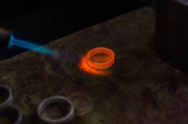 Profesyonel aletlerle mücevher yapımı. Makro atış. El yapımı kuyumcu, mücevher üretimi. Eriyen metal