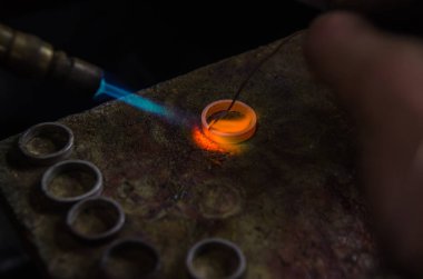 Profesyonel aletlerle mücevher yapımı. Makro atış. El yapımı kuyumcu, mücevher üretimi. Eriyen metal
