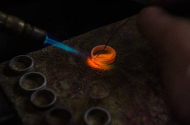 Profesyonel aletlerle mücevher yapımı. Makro atış. El yapımı kuyumcu, mücevher üretimi. Eriyen metal