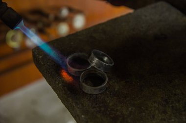 Profesyonel aletlerle mücevher yapımı. Makro atış. El yapımı kuyumcu, mücevher üretimi. Eriyen metal