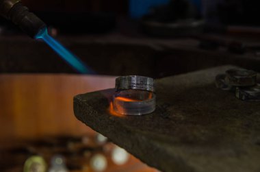 Profesyonel aletlerle mücevher yapımı. Makro atış. El yapımı kuyumcu, mücevher üretimi. Eriyen metal