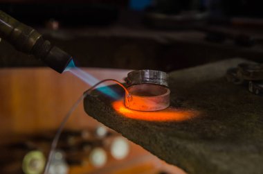 Profesyonel aletlerle mücevher yapımı. Makro atış. El yapımı kuyumcu, mücevher üretimi. Eriyen metal