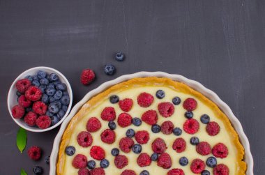 Siyah ahşap arka plan üzerinde vanilya krem ile Lezzetli Yaban Mersini tartlets. Üst te. şekerleme kavramları, fırın konsepti