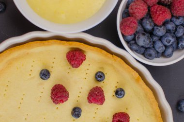 Siyah ahşap arka plan üzerinde vanilya krem ile Lezzetli Yaban Mersini tartlets. Üst te. şekerleme kavramları, fırın konsepti