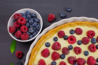 Siyah ahşap arka plan üzerinde vanilya krem ile Lezzetli Yaban Mersini tartlets. Üst te. şekerleme kavramları, fırın konsepti