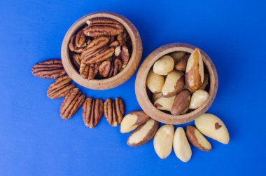 Mavi arka planda Pekan ve Brezilya fındıkları. Sağlıklı yemek.