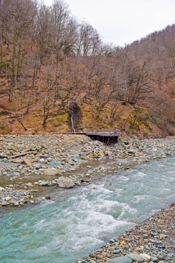  Güzel bir dağ manzarası, bir orman tepesi arasında mavi bir nehir, ahşap bir teras ve küçük bir şelale..