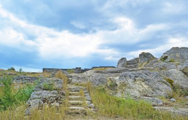  Eski bir merdivenin güzel manzarası, sarı ve yeşil çimenlerin arasındaki taşlar mavi gökyüzü ve bulutlu, beyaz bulutlar