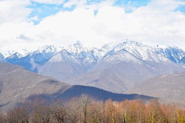  Cumulus 'un güzel manzarası, dağların ve ormanın karlı zirvesinin üzerinde gölgeleri olan beyaz, büyük bulutlar.