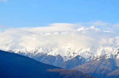  Uçan güzel manzaralar, karlı dağların tepesinde beyaz bulutlar ve mavi gökyüzü.
