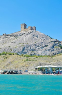 Yüksek gri bir kaya ve turkuaz deniz üzerindeki kalenin güzel manzarası..