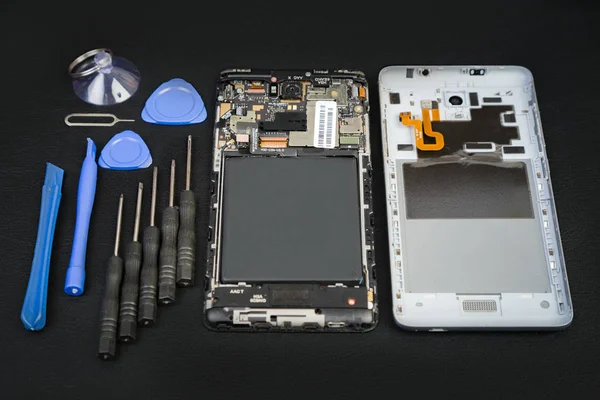 Demonte telefon ve özel amaçlı araçlar siyah masada. Smartphone ayrıntıları.