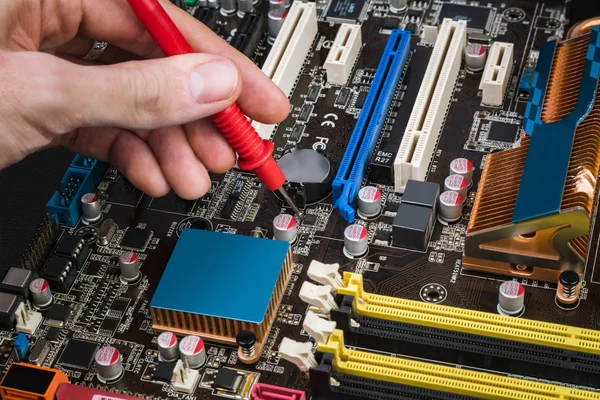 İşyeri tamirci bilgisayarlar. Siyah bir iş istasyonunda bir Voltmetre ile eski bir anakart tamir