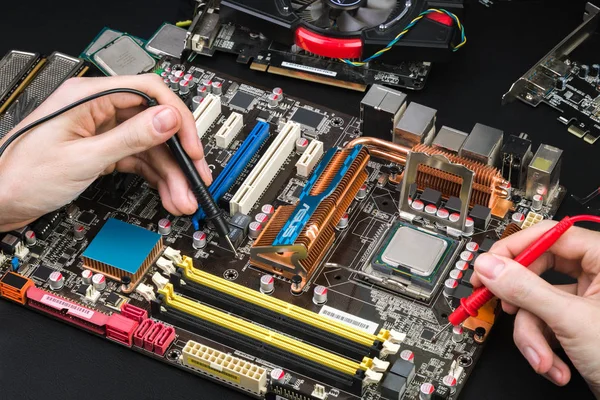 Siyah bir tabloda bir Voltmetre ile eski anakart teşhis. Özel araçlar ve demonte bilgisayar ile İşyeri tamirci