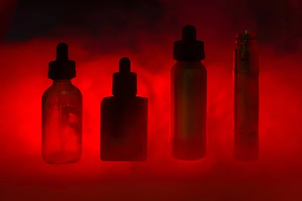 E Sigara üç e-sıvı duman koyu kırmızı arka plan ile. E-suyu vape rengi. Alternatif sigara