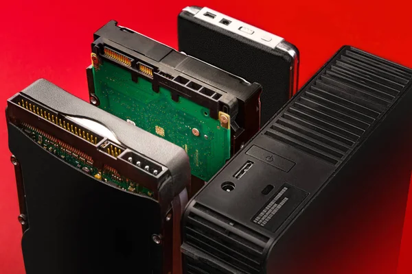 Kırmızı bir arka plan üzerindeki bir bilgisayara bağlanmak için IDE, sata ve usb konektörlerine iç ve dış sert götürmek. Hdd gelişimi öyküsü. Depolama teknolojisi.