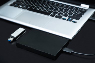 Harici sabit disk dizüstü bilgisayar ve siyah bir arka plan üstünde Usb birden parlamak götürmek bağlı. Taşınabilir veri depolama kavramı