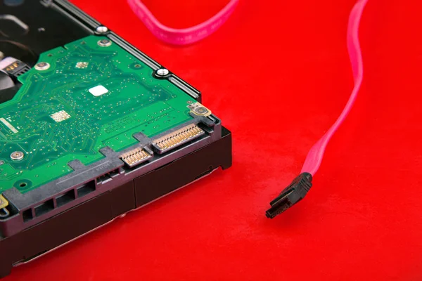 Part of the hard drive and the sata cable on the red table