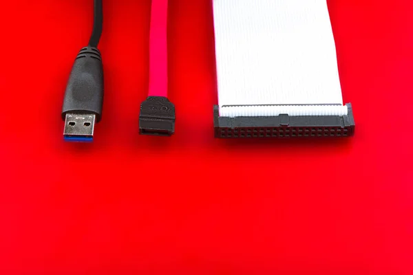 Sata cable, usb and ide cables on the red desktop.  The concept of data storage