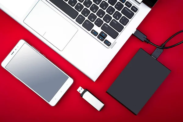 Taşınabilir hdd usb birden parlamak götürmek ve kırmızı bir arka plan, düz yatıyordu smartphone ile bir dizüstü bilgisayara bağlı. Veri depolama kavramı