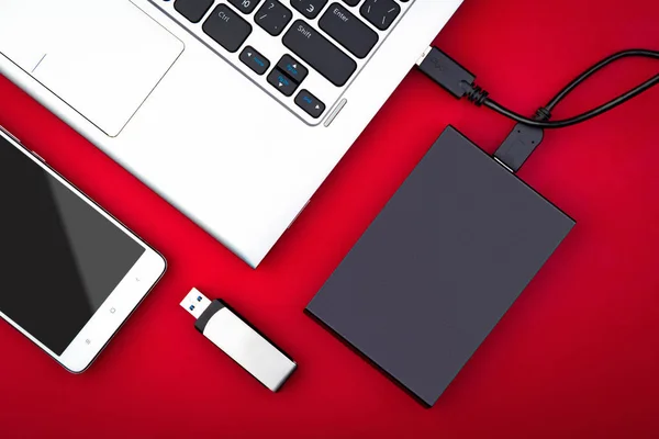 Harici sabit disk dizüstü bilgisayar, Usb birden parlamak götürmek ve kırmızı bir arka plan, düz yatıyordu Smartphone'da bağlı. Mobil teknoloji kavramı