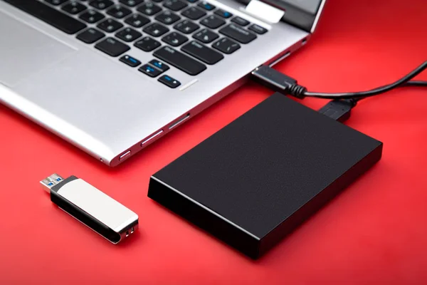 Taşınabilir hdd bir dizüstü bilgisayar ile usb birden parlamak götürmek kırmızı bir masaya bağlı. Veri depolama kavramı