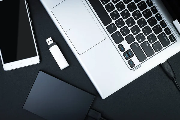 Dizüstü bilgisayar, Usb flash sürücü ve bir siyah arka plan, üstten görünüm smartphone harici hdd bağlı. Taşınabilir veri depolama kavramı