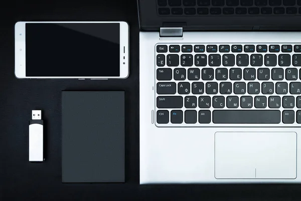 The concept of data storage. A portable hdd connected to a laptop with usb flash drive on a black table, flat lay.
