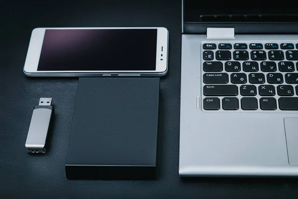 External hdd with the laptop, USB flash drive and smartphone on a black background. The concept of portable business technology